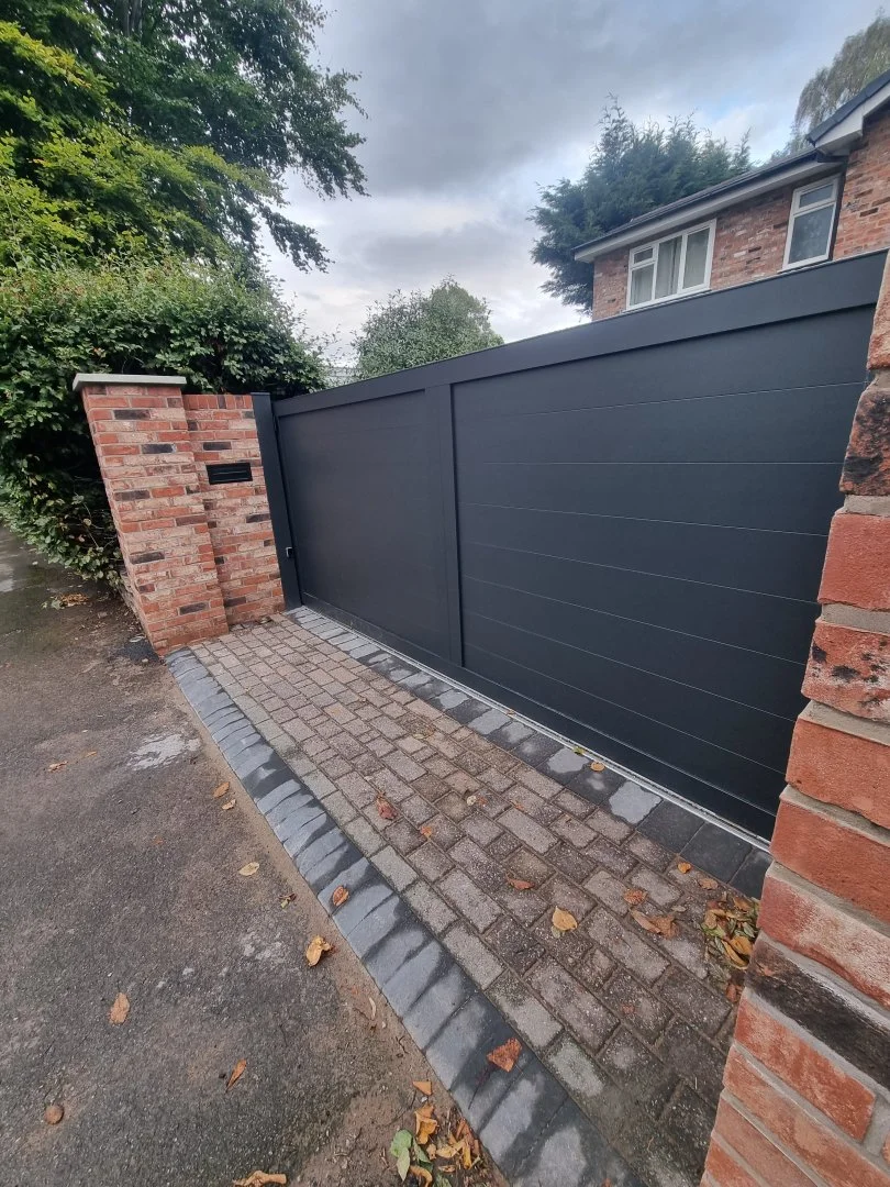 Dark sliding driveway gate beside brick entrance pillars