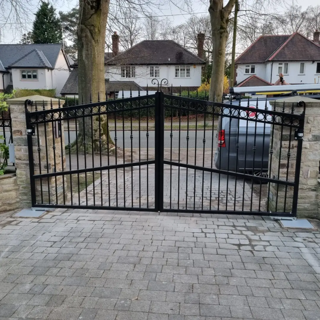 Black metal double driveway gates across a paved entrance