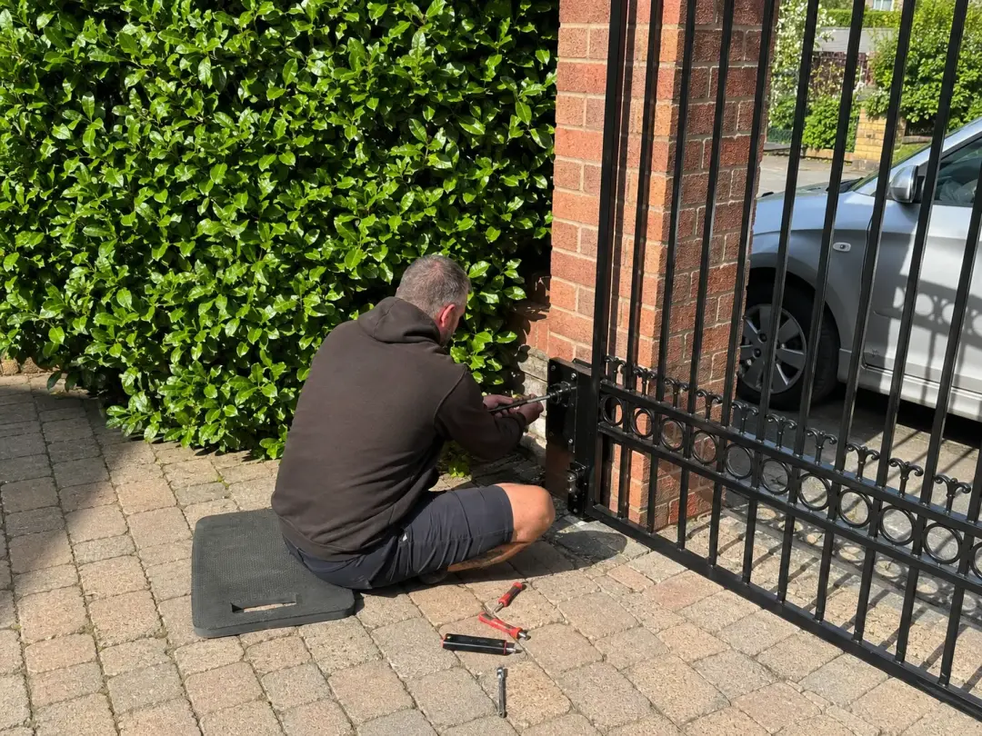 Technician working on the hinge of a metal driveway gate
