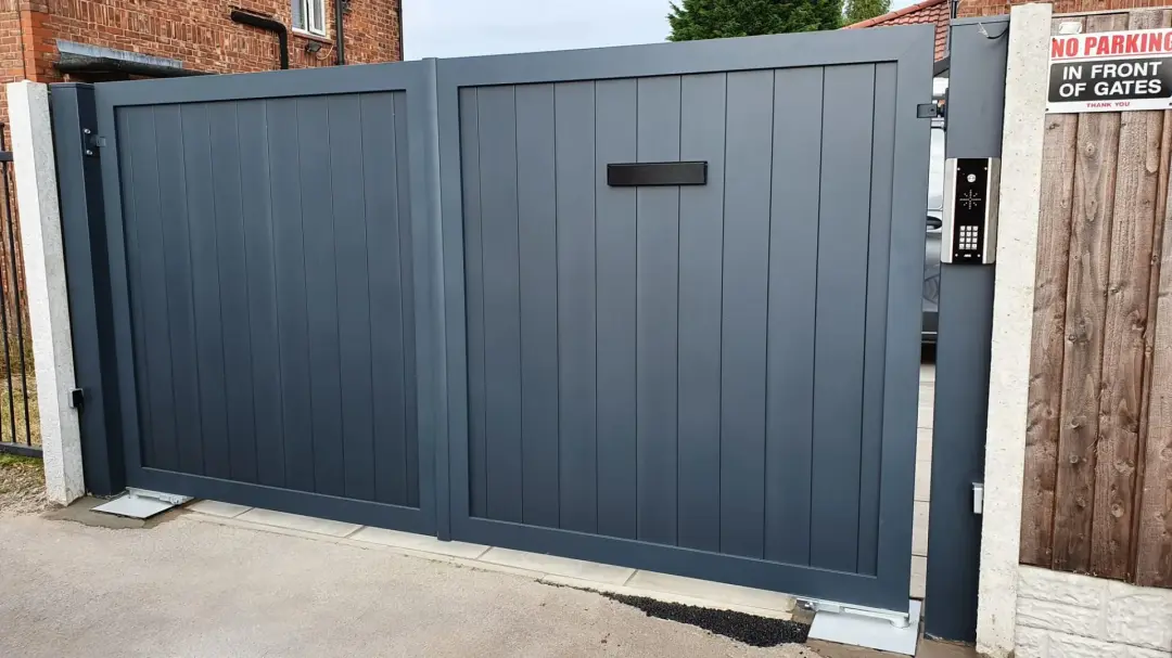 Grey double driveway gates with an intercom keypad beside the entrance